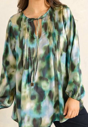 Blouse à manches longues avec motif aquarelle vert, bleu et noir, détails plis plats et col noué avec accents de perles dorées.
