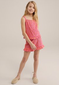 Růžový květinový dvoudílný outfit zahrnující top s volánovým lemem a nastavitelnými ramínky spolu s odpovídajícími šortkami s podobným designem a volánovými okraji.