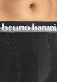Svarta bomullboxershorts med en grå midjeband som har "bruno banani"-logotypen. Texturen ser slät ut med platta sömmar.