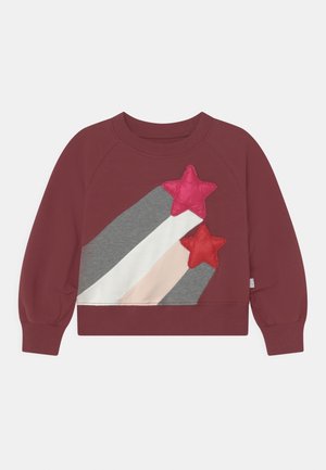 Sweatshirt à manches longues bordeaux avec des rayures diagonales grises, blanches et roses, et deux patchs étoile gonflants en rose et rouge sur le devant.