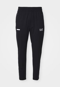 Fekete sportnadrág puha anyagból, rugalmas derekú, két cipzáras oldalzsebbel és fehér logó részletekkel.