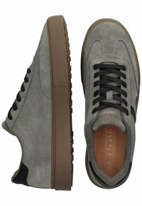 Pilki zomšiniai sportbačiai su tekstūruota paviršiumi, juodomis raištelėmis, rudais guminais padais ir juodu odiniu kulno akcentu.