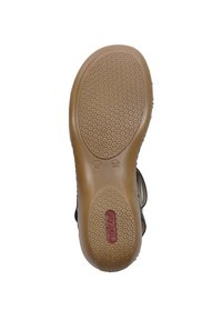 Semelle de chaussure en caoutchouc avec un motif de crampons hexagonaux, de couleur beige avec un logo rouge intégré près du centre, et un bord lisse et arrondi.