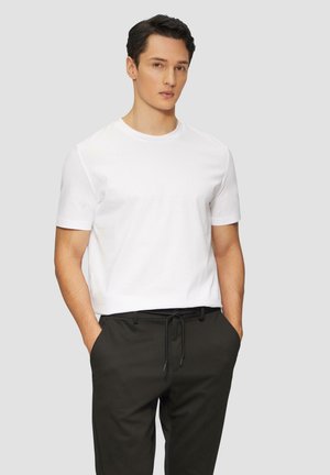 White short-sleeve t-shirt made of cotton, featuring a crew neck and a relaxed fit, paired with black drawstring pants.