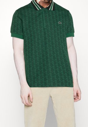 Grünes Poloshirt aus strukturiertem Stoff mit Diamantmuster, kontrastierendem gestreiftem Kragen und gesticktem Logo auf der Brust.