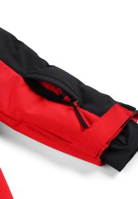 Manica di giacca rossa e nera con tasca con zip, pannelli di tessuto a contrasto e dettagli del polsino regolabili. Texture liscia, materiale resistente.