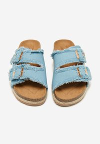 Sandalias deslizantes de denim azul con bordes deshilachados, dos correas ajustables y una planta de corcho color marrón. Cuenta con detalles en dorado.