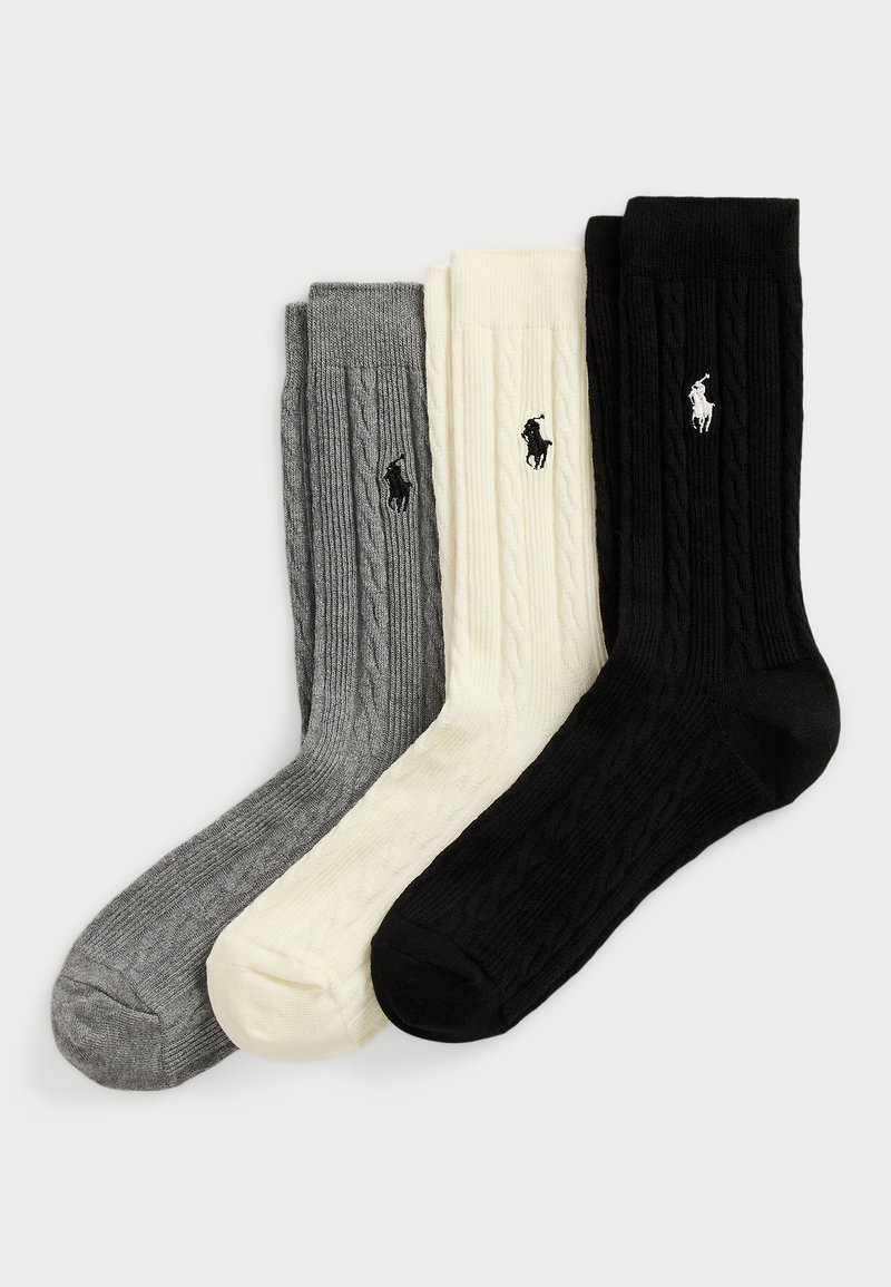 Trois paires de chaussettes en tricot côtelé de couleur gris, crème et noir, avec un logo brodé près du haut de chaque chaussette.
