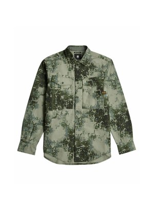 Camicia a maniche corte con bottoni in un motivo a camouflage pixelato verde. Presenta due taschini sul petto e un orlo arrotondato. Materiale in cotone.