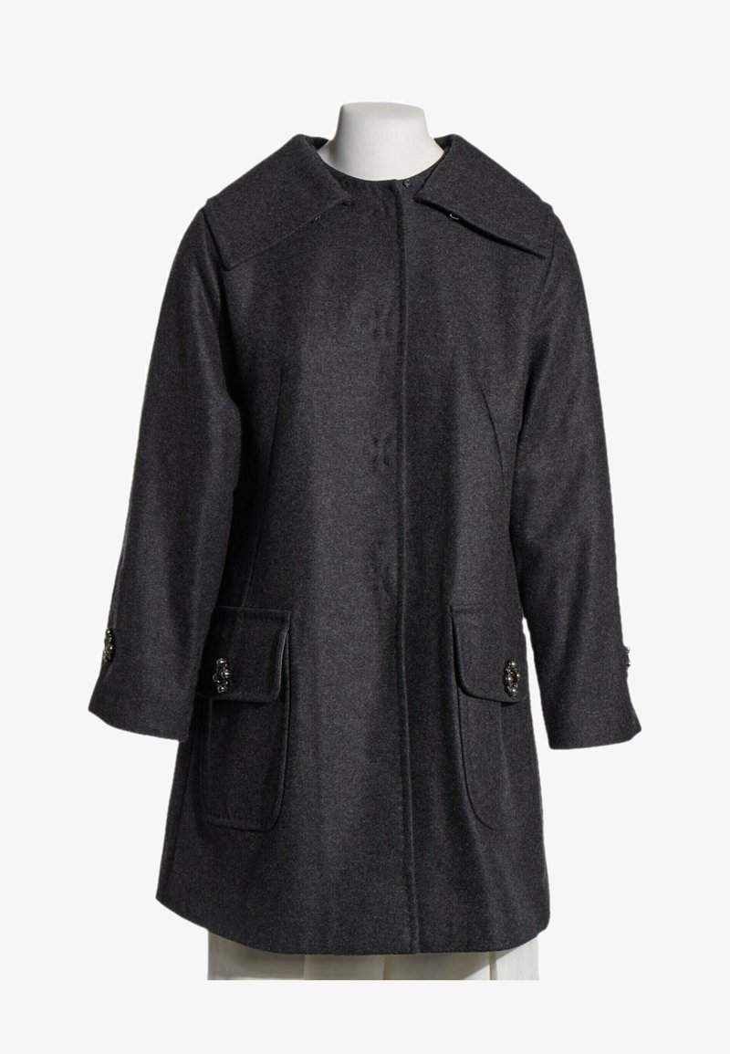 Manteau en laine gris foncé avec grand col, boutons avant cachés par une patte, manches longues et poches à rabat avec boutons décoratifs.