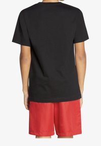 Czarna bawełniana koszulka z krótkimi rękawami, okrągłym dekoltem i luźnym krojem, połączona z czerwonymi szortami z gładkiego materiału.