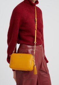 Gul pebble læder crossbody taske med en guld kædestropp og frynse detaljer. Rektangulær form med en tekstureret finish. Sølv hardware accenter.