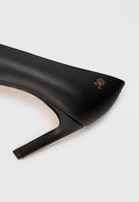 Black leather high-heeled pump featuring a slim heel and a small gold logo near the back of the shoe.