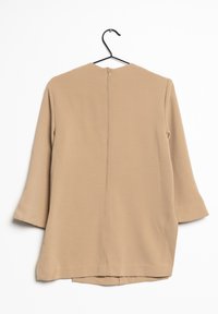 Top beige di lunghezza media con maniche a tre quarti, scollatura rotonda e zip centrale sul retro. Texture liscia, design semplice e senza fantasie.