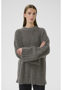 Sivi pleteni pulover, mehak na dotik, oversized kroj, rebrasti manšeti, okroglo izrezan ovratnik, sega pod boke, združen z temnimi jeans.
