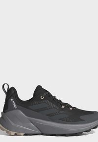 Chaussure de trail Adidas Terrex noire et grise avec semelle texturée, laçage à l'avant et languette au talon.
