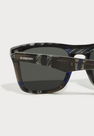 Burberry sunglasses with a black and blue patterned frame, dark lenses, and a branded temple detail. Made from lightweight plastic material.