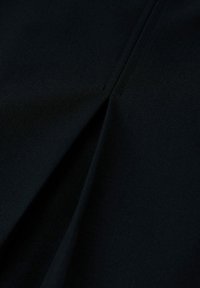 Tessuto nero con una texture liscia, caratterizzato da una piega decorativa e cuciture pulite, che creano un aspetto strutturato.
