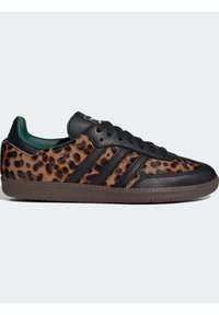 Lage sneakers met panterprintbont, zwarte leren accenten, zwarte veters, bruine rubberen zool en donkergroene binnenvoering, zijaanzicht.