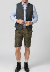 Grau gestrickte Weste mit silbernen Knöpfen, blau kariertes Hemd, braune Lederhosen mit Stickerei und schwarze Stiefel mit grauen Socken.