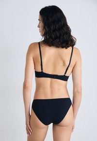 Schwarzes Bikini-Set mit minimalistischem Design, verstellbaren Trägern und einem Verschluss am Rücken. Glatte Textur ohne sichtbare Muster.