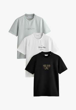 Three t-shirts in light green, white, and black. Each has a round neck; white and black feature printed text in contrasting colors.