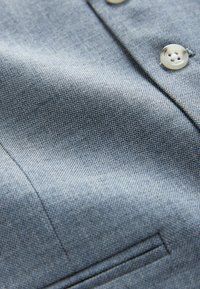 Material denim cu o nuanță albastru-gri, având o textură subtilă și cusături vizibile. Include două butoane bej și un detaliu de buzunar.