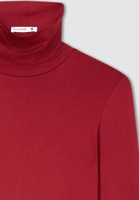 Czerwona koszulka z golfem, uszyta z miękkiego materiału, z wysokim kołnierzem, długimi rękawami i elegancką, gładką fakturą. Widoczna metka rozmiaru.