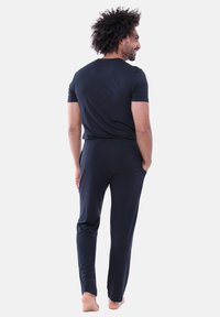 Czarny t-shirt z krótkim rękawem w połączeniu z czarnymi spodniami dresowymi, wykonanymi z gładkiego, elastycznego materiału, charakteryzuje się luźnym krojem i elastycznym pasem.