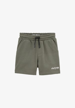 Olivgrüne Shorts mit elastischem Bund, schwarzem Kordelzug, seitlichen Taschen und weißem "SALTYDOG"-Schriftzug am linken Bein.