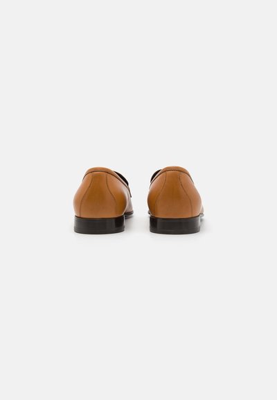 Leather dress shoes in tan, featuring a smooth finish, rounded toe, a low black heel, and minimal stitching details.