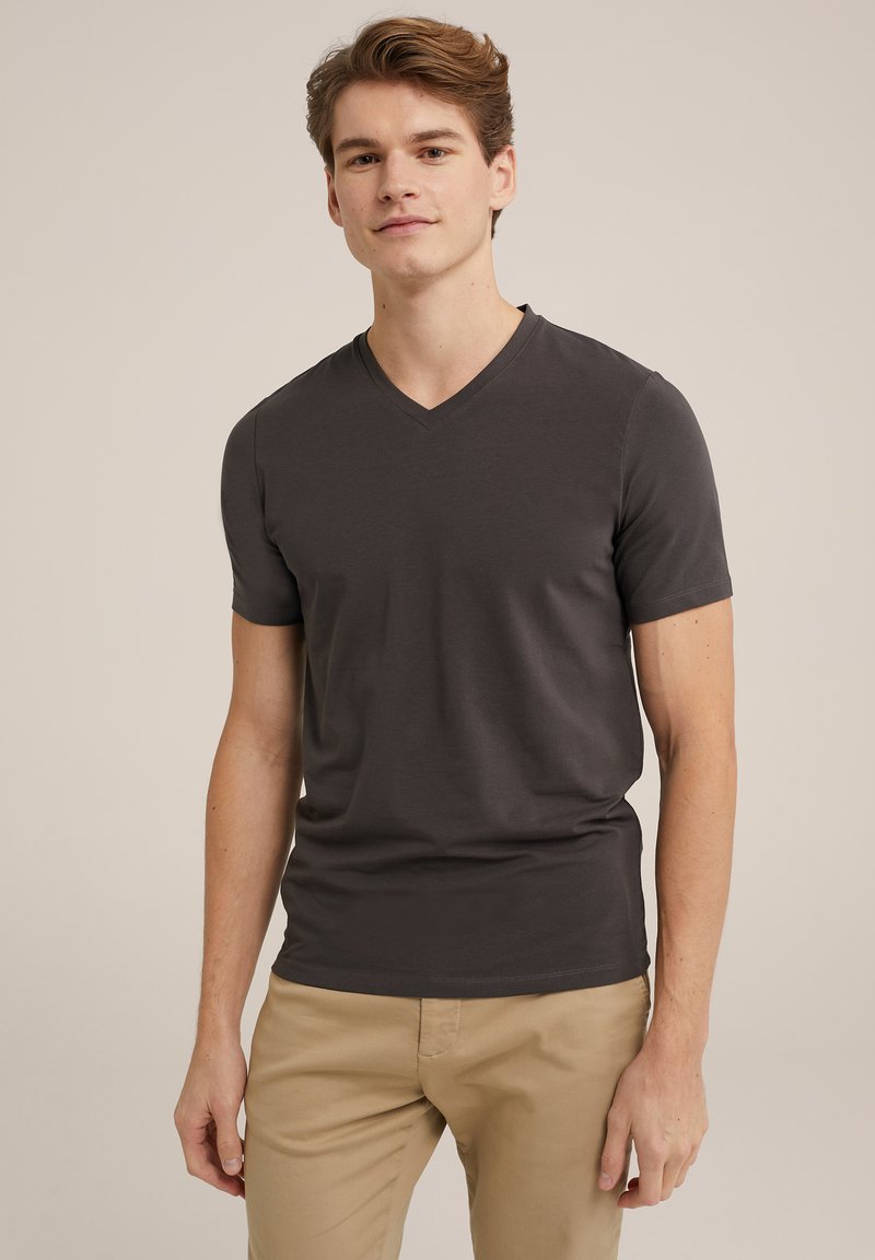 Camiseta gris de cuello en V en un diseño ajustado, hecha de tela suave con mangas cortas, combinada con pantalones beige. Apariencia simple y limpia.