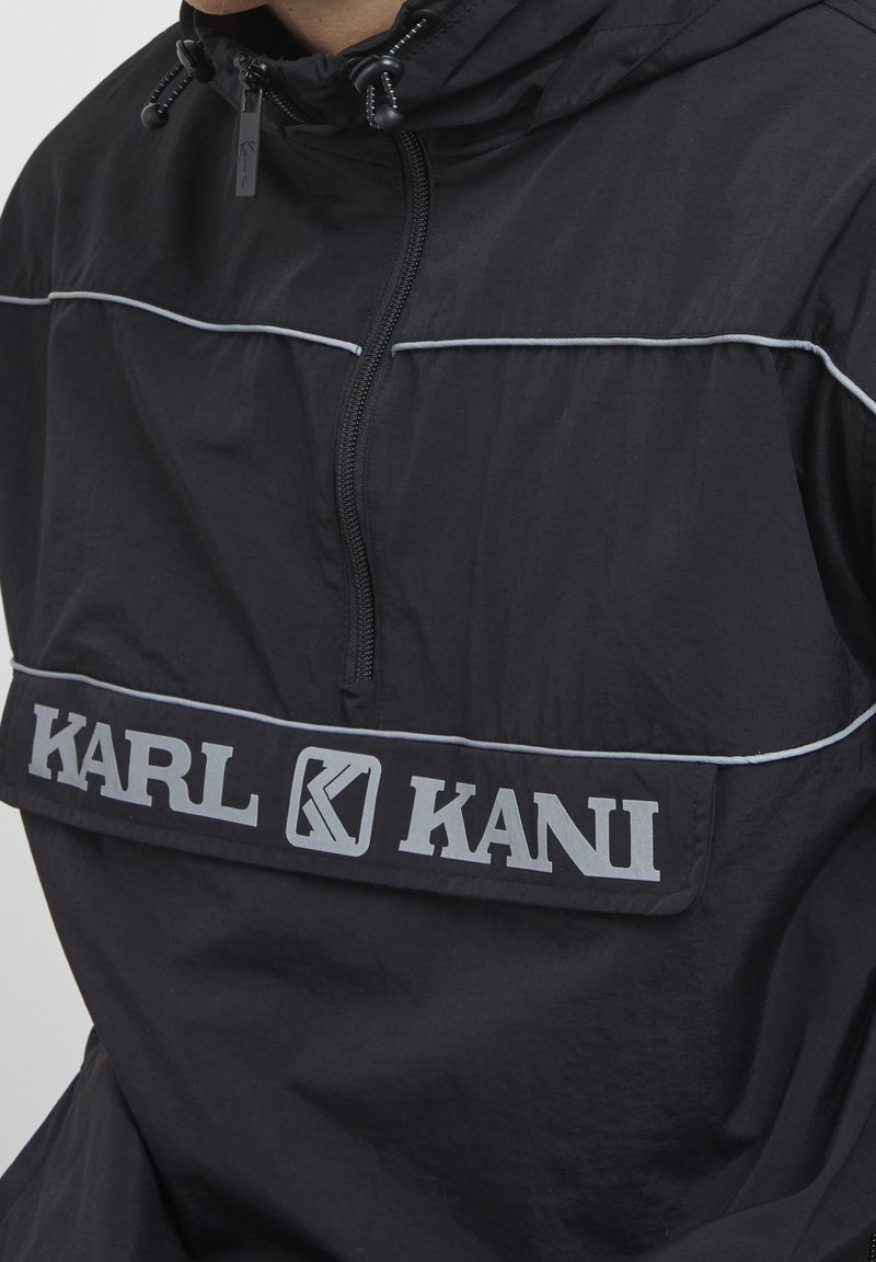 Black jacket with front zipper and "KARL KANI" logo in large reflective letters across the chest.