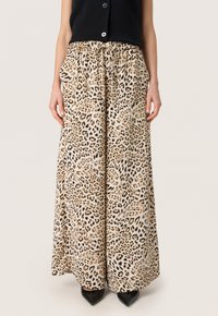 Leoparden gemusterte Culotte-Hosen mit einem elastischen Bund und seitlichen Taschen, aus leichtem Stoff gefertigt, kombiniert mit schwarzen Absatzschuhen.