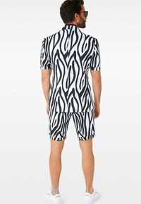 Set majice s kratkim rukavima i kratkim hlačama u crno-bijelom uzorku zebra, izrađeno od laganog materijala, s klasičnom ovratnikom i usklađenim dizajnom.