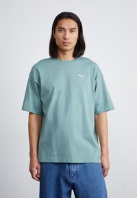 Tricou din bumbac verde, cu guler rotund și mâneci scurte. Prezintă un mic logo Puma alb pe piept și un design confortabil.