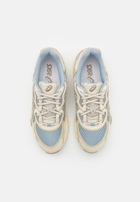 Ljusblå nät och beige syntetisk sneakers med grå detaljer och vita snören. Har texturerade paneler och en dämpad sula.