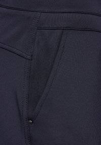 Navy stretch pants with a smooth texture, featuring a side pocket with visible stitching and a small metal button accent.