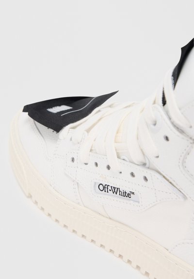 Valge nahast spordijalats tekstureeritud pinnaga, millel on must silt, Off-White'i logo ja paks kummist tald koos tuntava mustripatterniga.