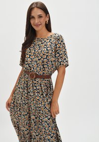 Kwiatowa sukienka maxi z krótkimi rękawami, z granatowym tłem, białymi i pomarańczowymi kwiatami oraz brązowym paskiem w talii. Gładka tekstura materiału.