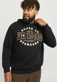 Czarna bluza z kapturem wykonana z bawełny, z dużym białym i pomarańczowym nadrukiem graficznym z nazwą marki "Jack & Jones" oraz luźnym krojem.