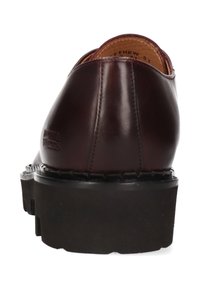 Brązowy skórzany but z zaokrąglonym noskiem, czarną gumową podeszwą i widocznym przeszyciem. Posiada wytłoczone logo po boku.