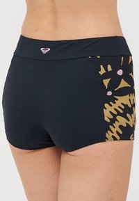 Black swim shorts with a detailed gold and pink pattern on the sides, featuring a wide waistband and a smooth texture.