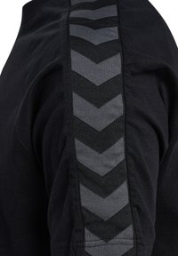 Mustast kangast vertikaalne hall triibuline kalasaba muster riide varrukal.