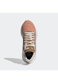 Light pink athletic shoe with a textured upper, beige sides, and white sole. Features flat laces and a brown branded tag on the tongue.