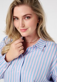Chemise col en bleu clair avec des rayures verticales roses et blanches, dotée d'une fermeture à boutons, d'un tissu lisse et de manches retroussées.