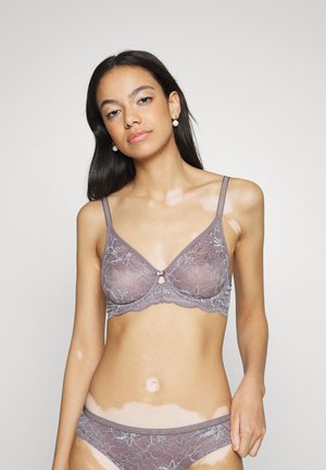 Lys lilla blonde bh med blomsterdesign, gennemsigtig stof, underwire støtte, justerbare stropper og en lille frontdetalje i form af et charme.