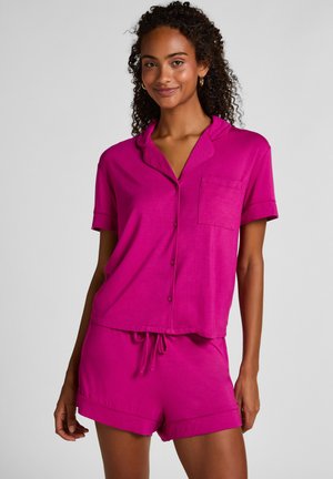 Pyjamaset in levendig fuchsia, bestaande uit een kort mouwenshirt met knopen en een borstzakje, gecombineerd met bijpassende shorts met trekkoord. Gladde stof.