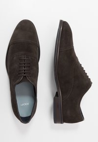 Chaussures habillées en daim marron avec un bout rond, un laçage sur le devant, des détails en surpiqûre et un talon bas. Doublure intérieure bleue.