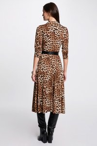 Robe à manches longues avec imprimé léopard, ceinturée de noir, avec une jupe fluide, confectionnée dans un matériau doux, associée à des bottes noires haute.